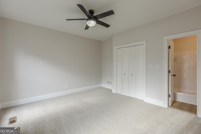 unfurnished bedroom featuring ceiling fan, a closet, ensuite bathroom, and carpet