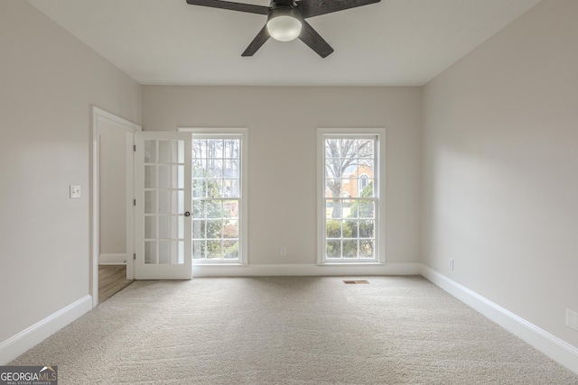 carpeted empty room with a healthy amount of sunlight and ceiling fan