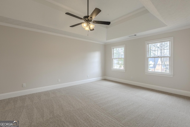 empty room featuring a raised ceiling, ornamental molding, light carpet, and ceiling fan