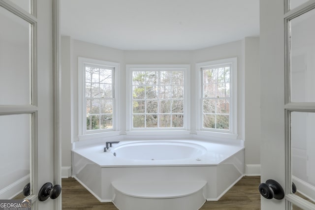 bathroom featuring a tub to relax in, wood-type flooring, and a wealth of natural light