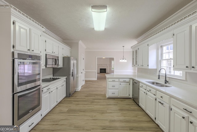 kitchen with sink, white cabinetry, hanging light fixtures, appliances with stainless steel finishes, and kitchen peninsula