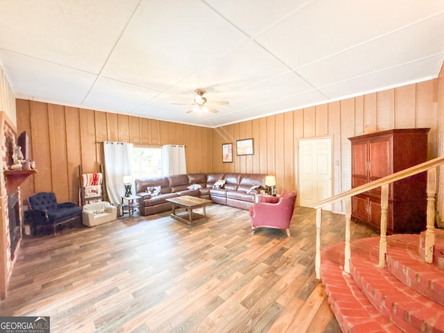 living room featuring wood-type flooring, ceiling fan, and wood walls