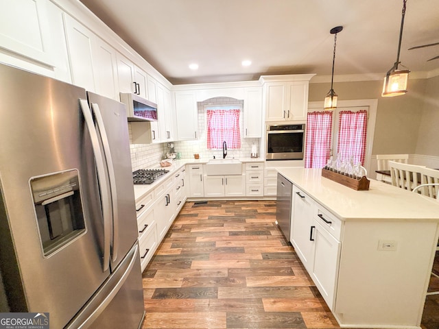 kitchen with pendant lighting, appliances with stainless steel finishes, sink, and white cabinets