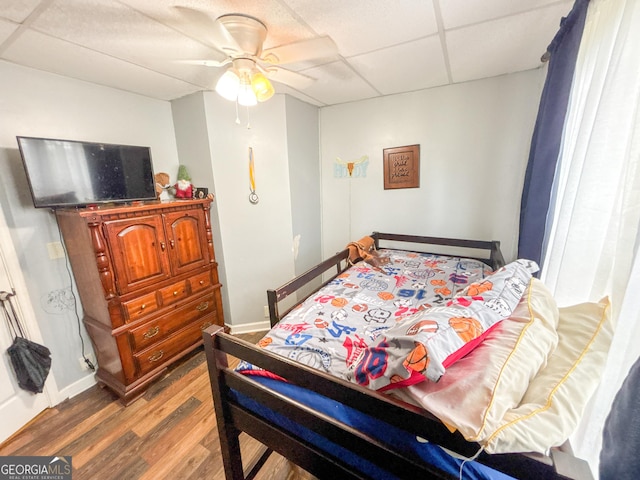 bedroom with hardwood / wood-style flooring, a paneled ceiling, and ceiling fan