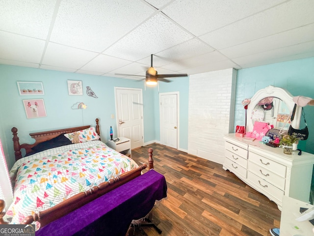 bedroom with a paneled ceiling, dark hardwood / wood-style floors, and ceiling fan