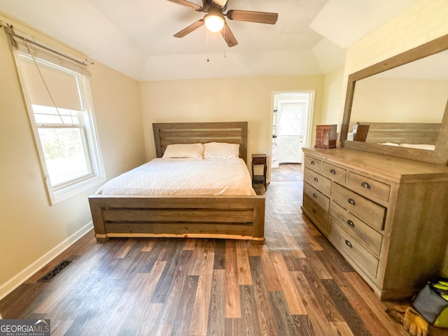 bedroom with dark hardwood / wood-style flooring, a tray ceiling, vaulted ceiling, and ceiling fan