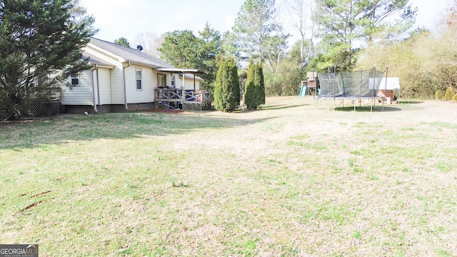 view of yard with a trampoline, a playground, and a deck