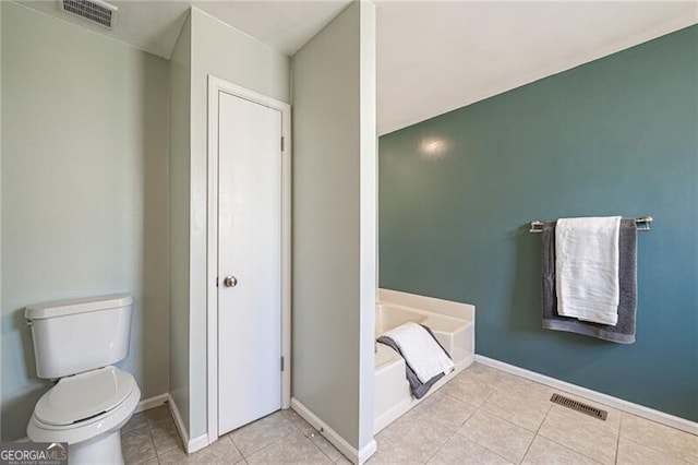 bathroom with tile patterned flooring, a bathtub, and toilet