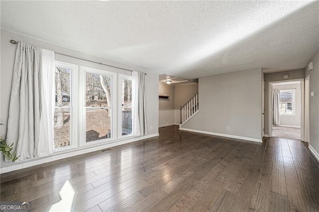 unfurnished room with dark hardwood / wood-style flooring and a textured ceiling