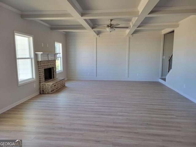 unfurnished living room with coffered ceiling, beam ceiling, a fireplace, and light wood-type flooring