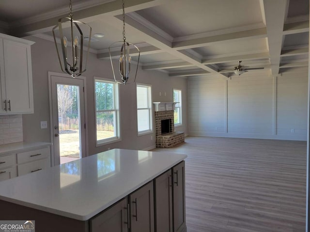 kitchen featuring beamed ceiling, white cabinetry, coffered ceiling, and light hardwood / wood-style flooring