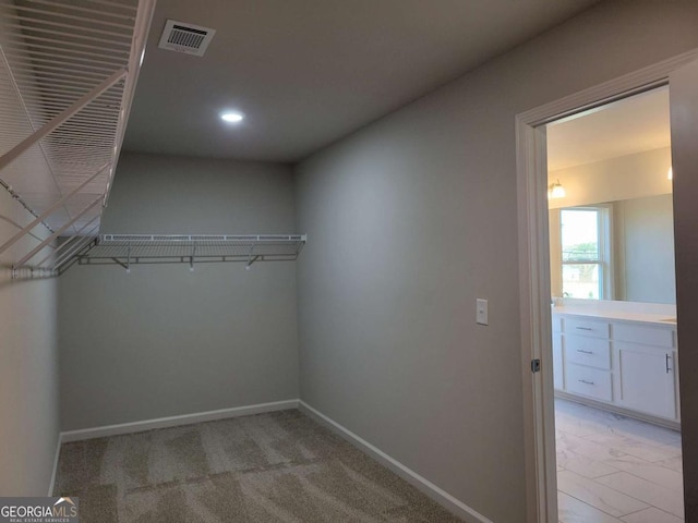 walk in closet featuring light carpet