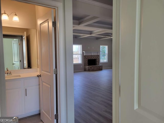 hall with sink, crown molding, dark wood-type flooring, beam ceiling, and coffered ceiling