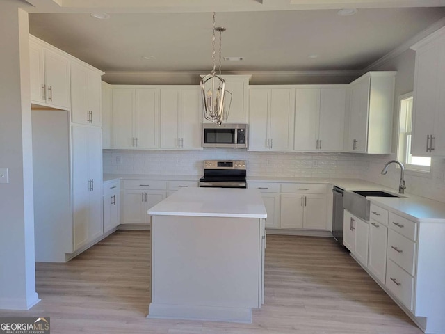 kitchen featuring sink, a center island, appliances with stainless steel finishes, pendant lighting, and white cabinets