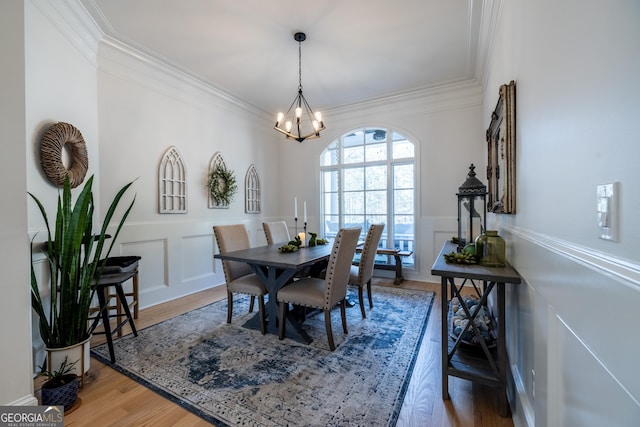 dining room with a notable chandelier, crown molding, and wood-type flooring