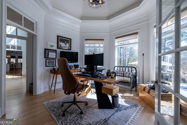 office space featuring hardwood / wood-style flooring, ornamental molding, a chandelier, and a towering ceiling