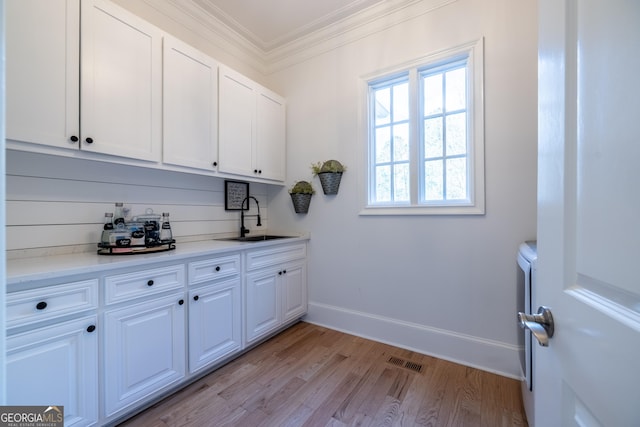 laundry area with sink, ornamental molding, and light wood-type flooring