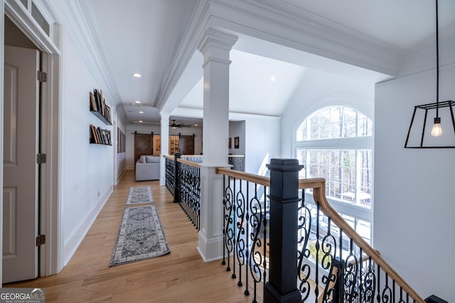 hallway with ornamental molding, decorative columns, and light wood-type flooring