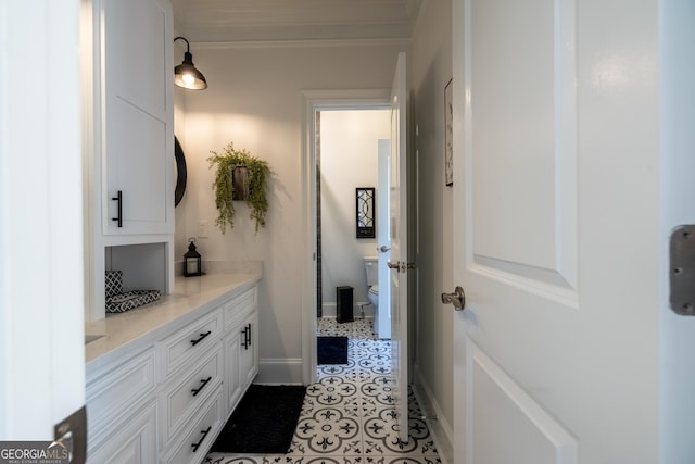 bathroom featuring tile patterned flooring, vanity, ornamental molding, and toilet