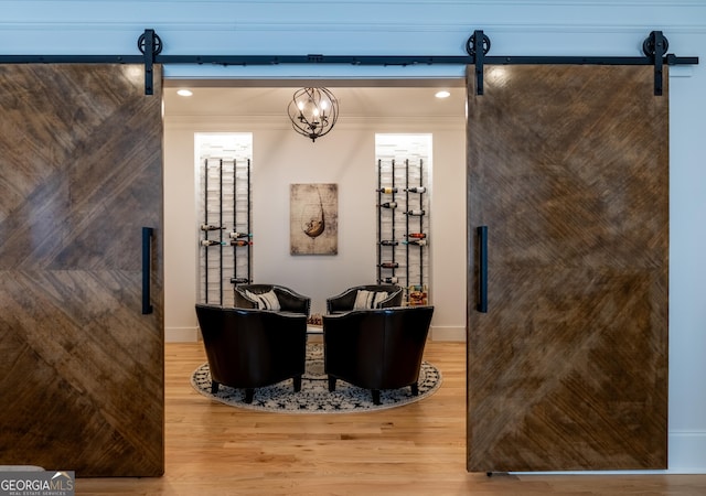 interior space with ornamental molding, wood-type flooring, and a barn door