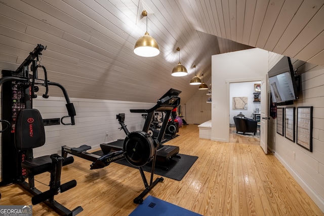 workout area featuring wood walls, lofted ceiling, wooden ceiling, and light hardwood / wood-style flooring