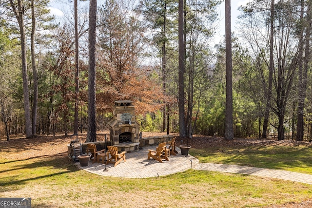 view of yard with an outdoor stone fireplace and a patio area