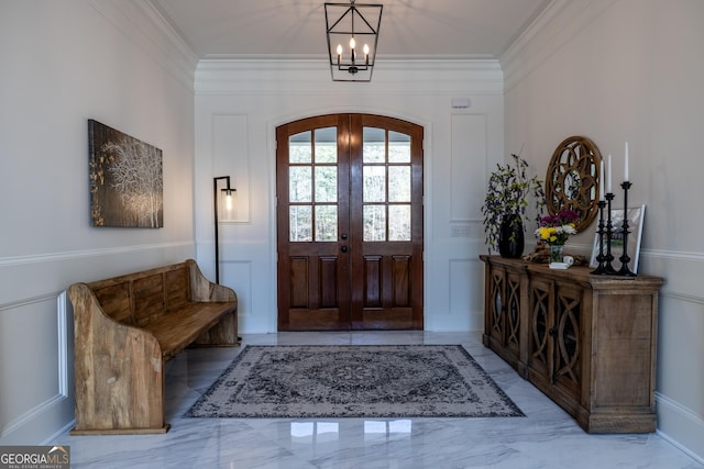 foyer featuring french doors, ornamental molding, and a notable chandelier