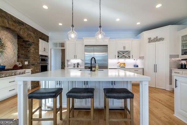 kitchen with hanging light fixtures, appliances with stainless steel finishes, a kitchen island with sink, and a breakfast bar