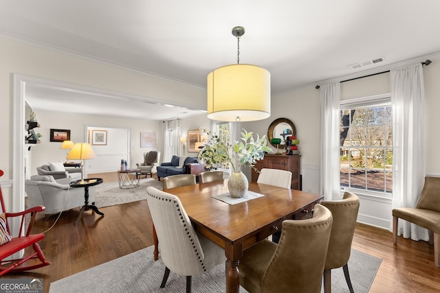 dining space featuring wood-type flooring and ornamental molding