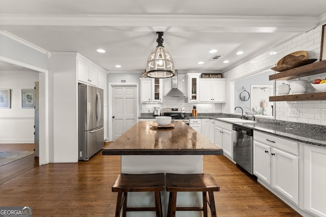 kitchen with stainless steel appliances, a center island, white cabinets, a kitchen bar, and wall chimney exhaust hood