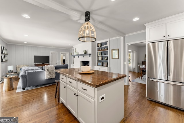 kitchen with stainless steel refrigerator, white cabinets, a center island, crown molding, and dark wood-type flooring