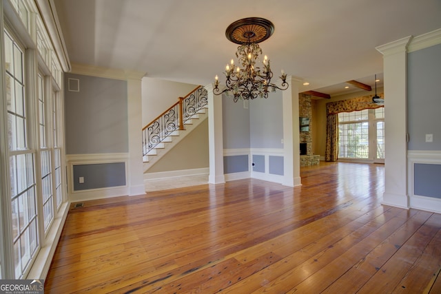 unfurnished living room featuring a brick fireplace, ornamental molding, hardwood / wood-style floors, and a chandelier