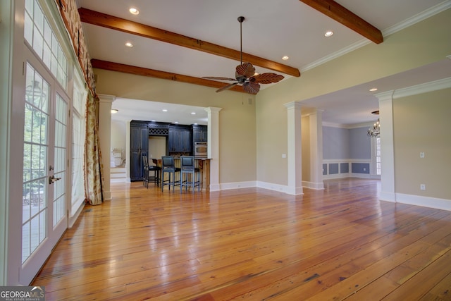 unfurnished living room featuring beamed ceiling, plenty of natural light, light hardwood / wood-style floors, and decorative columns