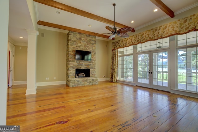 unfurnished living room with french doors, decorative columns, crown molding, beamed ceiling, and light hardwood / wood-style floors