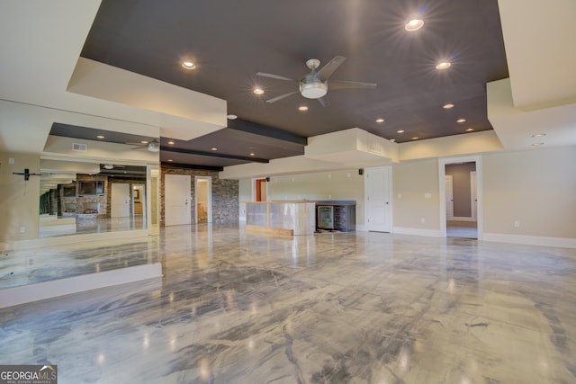 unfurnished living room with a raised ceiling and ceiling fan