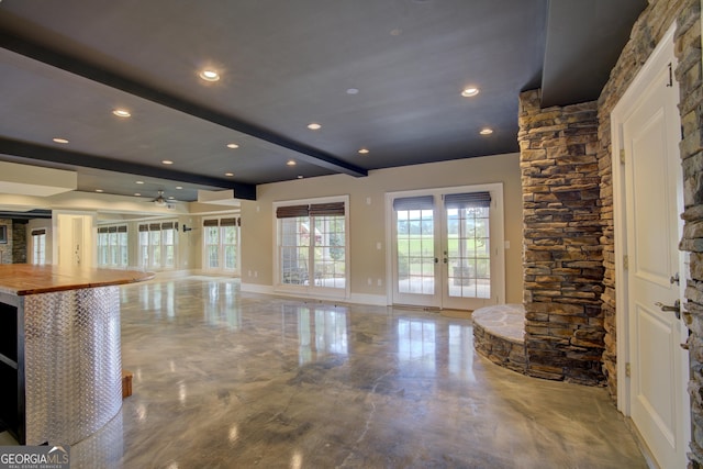 unfurnished living room featuring beam ceiling and french doors