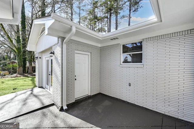 property entrance with french doors, a patio area, and brick siding