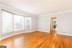 empty room with ornamental molding and wood-type flooring