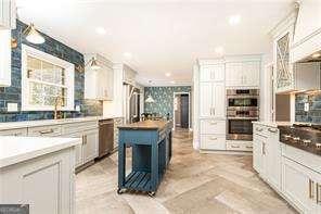 kitchen with sink, backsplash, white cabinets, and appliances with stainless steel finishes