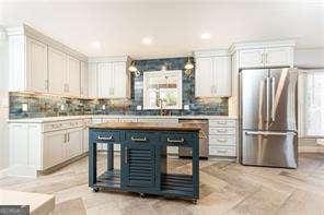 kitchen with backsplash, high end refrigerator, and white cabinets