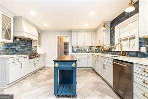 kitchen featuring tasteful backsplash, dishwasher, white cabinets, a center island, and custom range hood