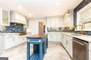 kitchen with white cabinetry, tasteful backsplash, dishwasher, and premium range hood