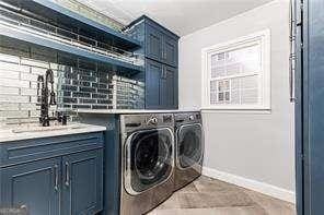 clothes washing area featuring cabinets, sink, and washing machine and clothes dryer