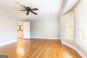 unfurnished room with hardwood / wood-style flooring, crown molding, and ceiling fan