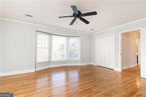 interior space with hardwood / wood-style flooring, ceiling fan, and ornamental molding