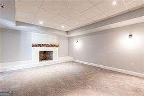 unfurnished living room with carpet floors, a raised ceiling, and a paneled ceiling