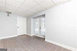 tiled spare room featuring a drop ceiling