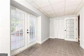 doorway featuring a paneled ceiling, dark tile patterned flooring, and french doors