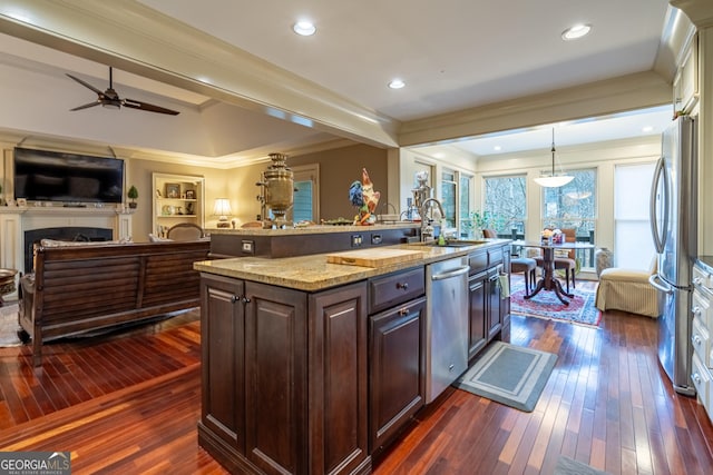 kitchen with sink, decorative light fixtures, dark brown cabinets, appliances with stainless steel finishes, and an island with sink