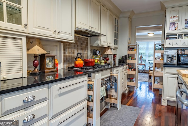 kitchen featuring tasteful backsplash, white cabinets, dark stone counters, crown molding, and dark wood-type flooring